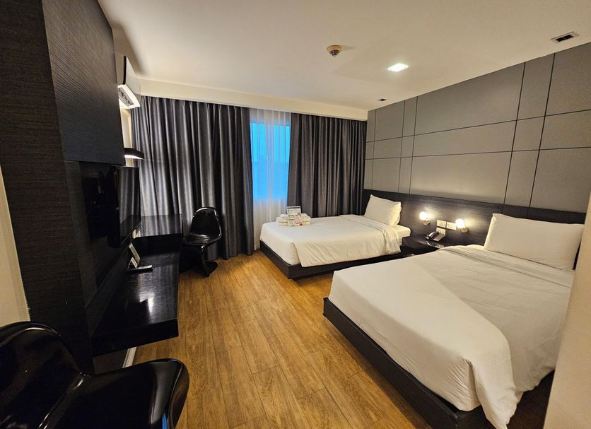 The Park Residence Bangkok room with two beds, desk, and dark curtains
