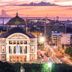 Hotel Dez De Julho in Manaus at sunset, with a domed historic building and river skyline beyond.