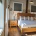 Old Mill Inn Hatfield guest room with wooden bed, nightstands, windows and wall art
