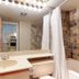 Glacier Lodge in Whistler bathroom with vanity, mirror, shower curtain, and tiled tub surround