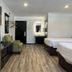 Home Suites Thief River Falls hotel room with two beds, TV, chair, and wood-look floor