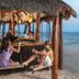 Hotel Marina El Cid Spa beach bar with guests on swings overlooking the ocean in Puerto Morelos