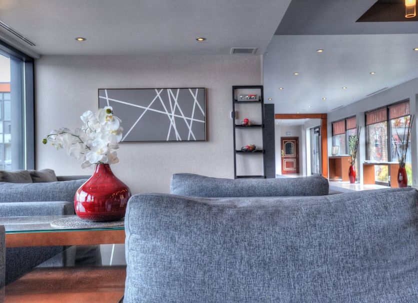 Hotel Forestel in Val-d'Or lounge with gray sofas, red vase centerpiece, and large windows