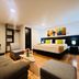 Hotel Ferias Park Bogotá guest room with king bed, sofa, chair, and colorful wall art
