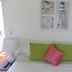Karibu Aruba in Noord guest room with bed, green pillows, pink accent pillow and bedside lamp