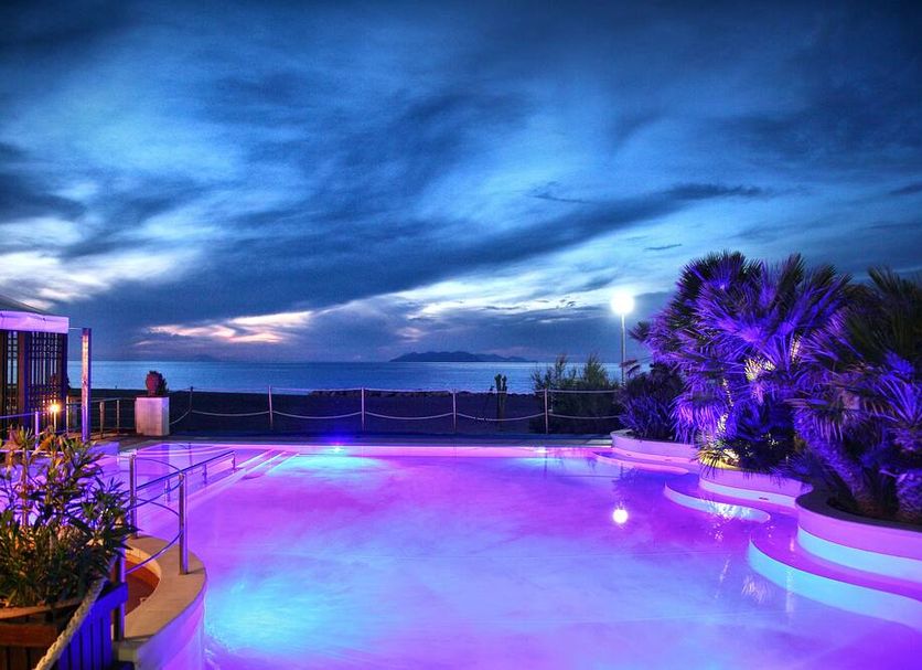 Hotel Il Gabbiano Beach in Terme Vigliatore features a lit rooftop pool with sea views at dusk