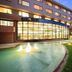 Kamenoi Hotel Fuji in Fujiyoshida, exterior with lit glass facade and curved fountain pool at dusk