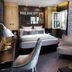Hôtel Baume in Paris guest room with open window, upholstered chair, and bed with mirrored headboard
