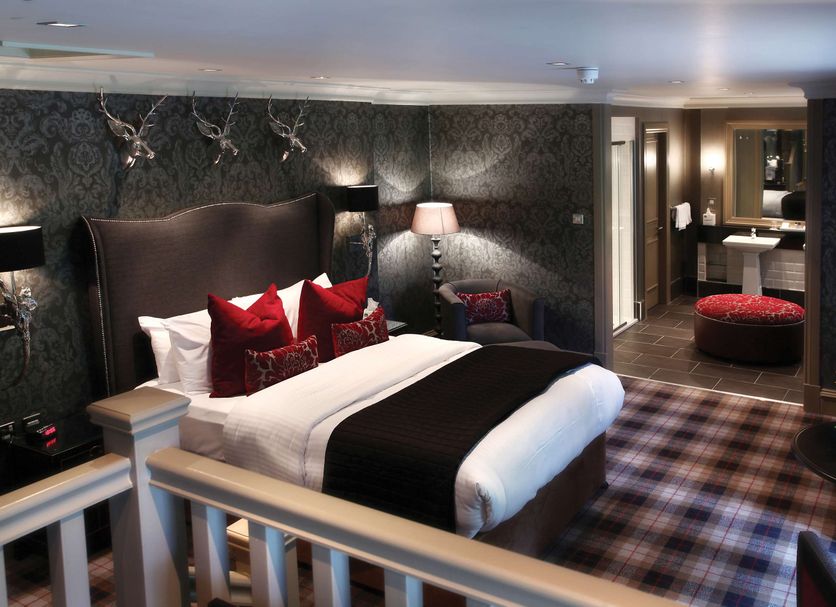 Eglinton Arms Hotel, Glasgow guest room with king bed, patterned wallpaper, lamps and plaid carpet