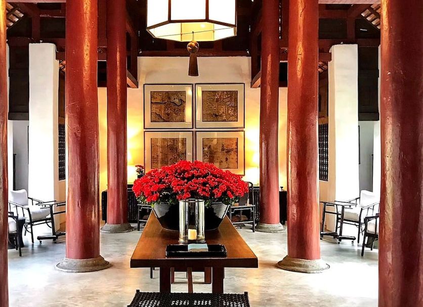 Rachamankha Hotel Chiang Mai lobby with red columns, central flower arrangement and hanging lantern