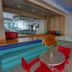 Ocean Beach Hotel Miami Beach lobby bar with colorful seating, mirrored wall, and curved glass-block counter