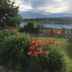 Bailey House in Annapolis Royal with garden flowers and lawn overlooking a calm waterfront at sunset