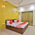 OYO 2494 Hotel Shree Plaza in Bharuch, guest room with double bed, yellow accent wall and curtains