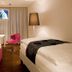 Zollamt Design Hotel Kaiserslautern guest room with bed, pink chair, desk, and window curtains