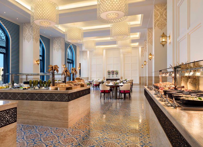 Al Najada Doha Hotel by Tivoli dining room in Doha with buffet stations and arched windows