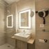 Logis Hotel Le Petit Casset in La Boisse bathroom with glass shower, lit mirror and wall-mounted sink