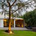 The Roseate New Delhi hotel exterior with lawn, trees, and lit open-air terrace at dusk