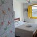 Pousada Fortaleza in Paraty room with bed, yellow-shuttered window, and open shelving