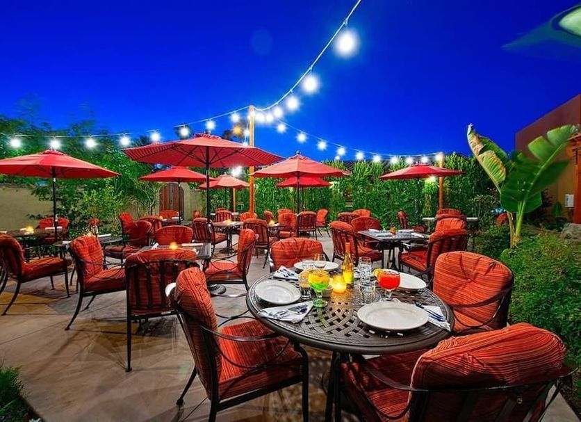 Los Arboles Hotel in Palm Springs outdoor patio with red umbrellas, string lights, and dining tables