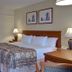 Vagabond Inn Ventura guest room with king bed, bedside lamps, desk, and attached vanity area