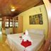 Baia Baia Resort in Ko Phi Phi guest room with bed, wall art, wood-paneled ceiling and open doorway to greenery