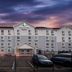 Woodspring Suites San Antonio South exterior at dusk with parking lot and dramatic sunset sky
