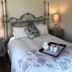 The Carriage House in Ocean Grove guest room with ornate metal bed and tea tray