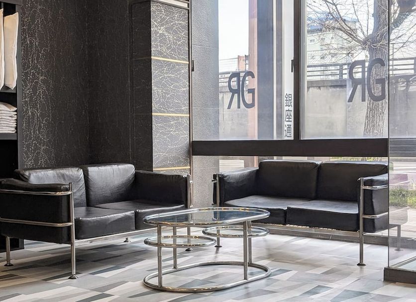 GR Hotel Ginzadori in Kumamoto lobby seating area with black sofas and a glass coffee table by large windows