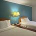 Motel 6 Portland, IN guest room with two beds, blue accent wall, lamp, and window