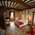 La Ferme de la Gronde in Bayeux: rustic guest room with wood beams, bed, window and hallway view