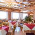 Hotel Scoiattolo in Falcade dining room with red tablecloths, floral chairs and ornate ceiling lights