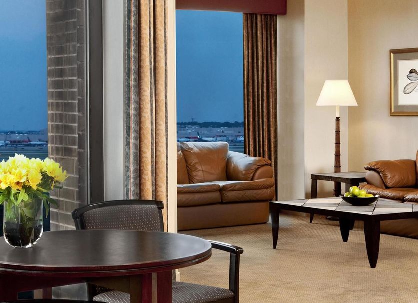 Sheraton Atlanta Airport Hotel suite with city view, sofa, lamp and dining table in Atlanta