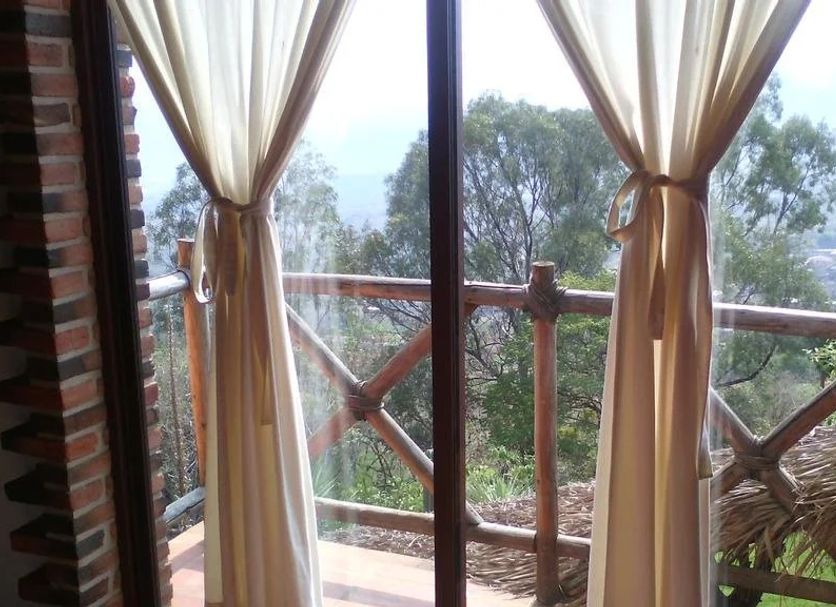 Oasis Tepoztlán in Tepoztlán, balcony view with curtains and treetops through glass doors