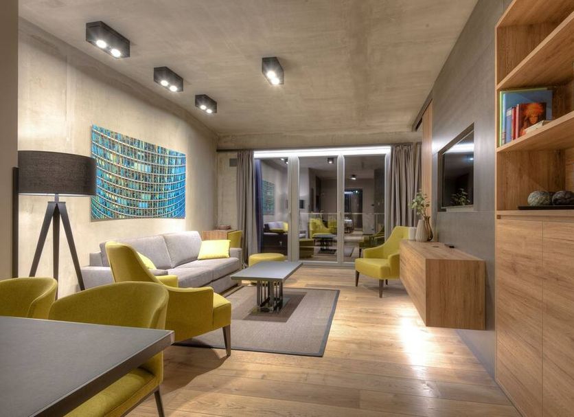 Downtown Apartments Mitte Berlin lounge with yellow chairs, sofa, coffee table and glass doors to balcony