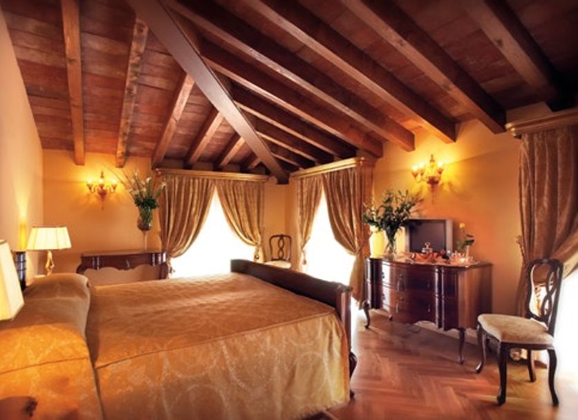 Villa Fenaroli Palace Hotel in Brescia, elegant suite with wood-beamed ceiling and canopy bed