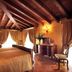 Villa Fenaroli Palace Hotel in Brescia, elegant suite with wood-beamed ceiling and canopy bed