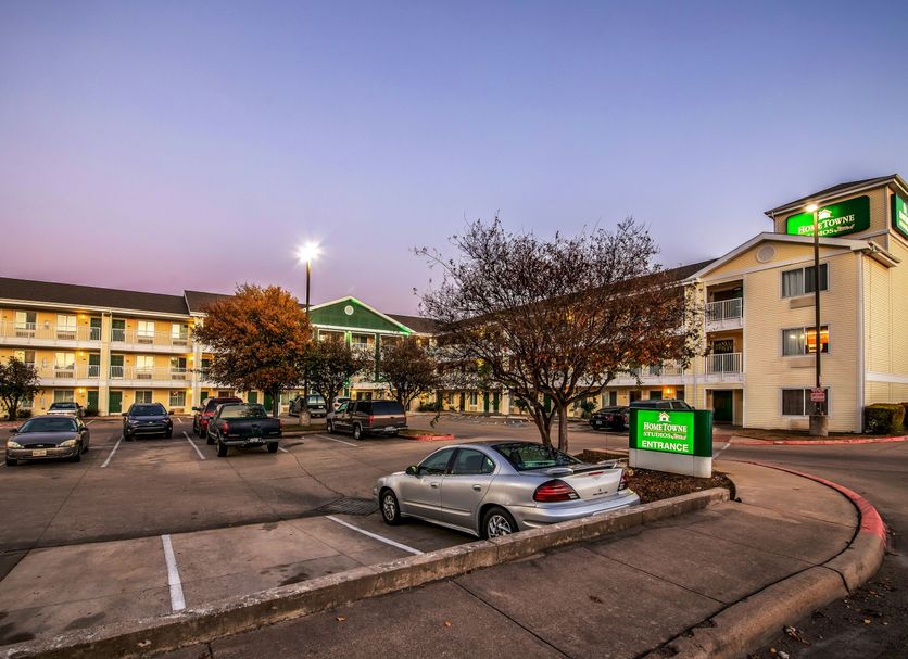 HomeTowne Studios by Red Roof Austin exterior with parking lot and lit guest rooms at dusk