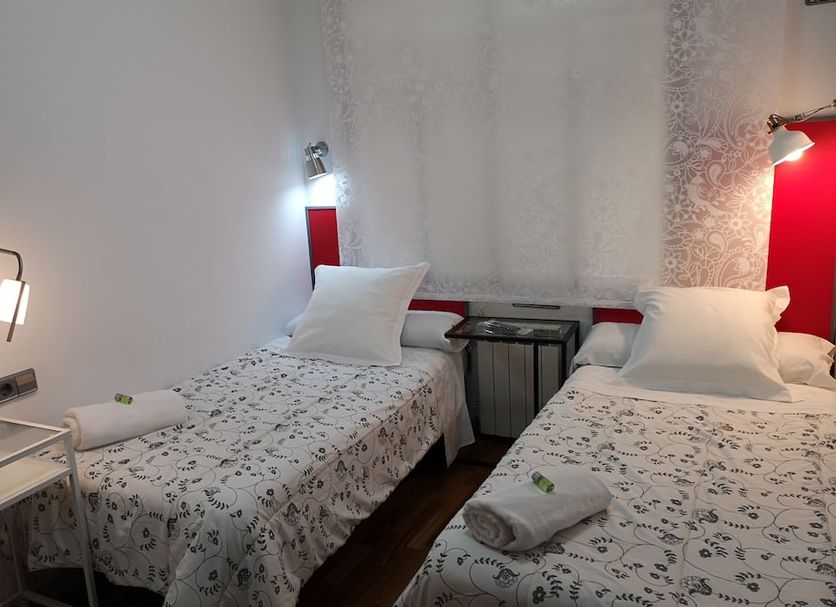 Hostal Carbonara in A Coruña twin room with two single beds, bedside lamps and white patterned bedding