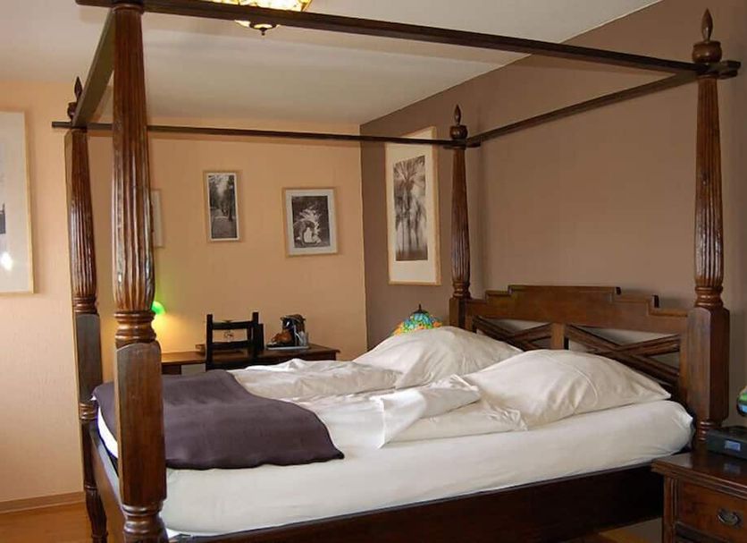 Four-poster bed in a room at the cosy home in Hodenhagen with framed wall art and bedside table.