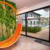 Pousada Flores do Carmo in Pirenópolis features a bright orange hanging chair beside a green plant wall and pool view.