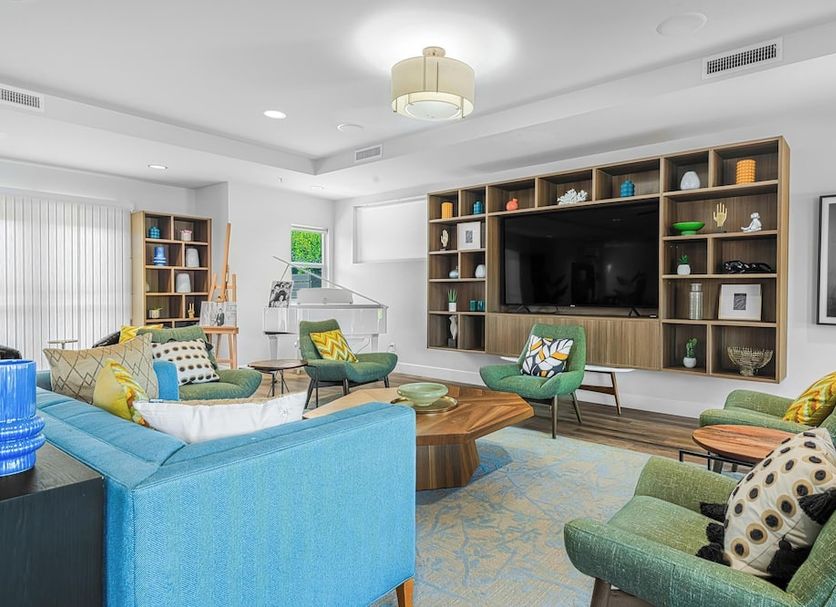 The Paloma Resort in Palm Springs lounge with blue sofa, green chairs, built-in shelves and TV