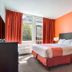 Motel 6 Surrey BC guest room with king bed, orange accent wall and window with red curtains