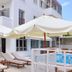 Erato Hotel in Agia Marina with poolside loungers, white umbrellas and a balcony outside the hotel