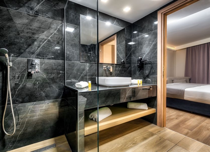 Palatino Hotel in Zakynthos bathroom with walk-in shower, stone vanity, and open view into the bedroom