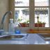 Villa Olivia Split sink view of stone wall, potted plants and tiled roof through window