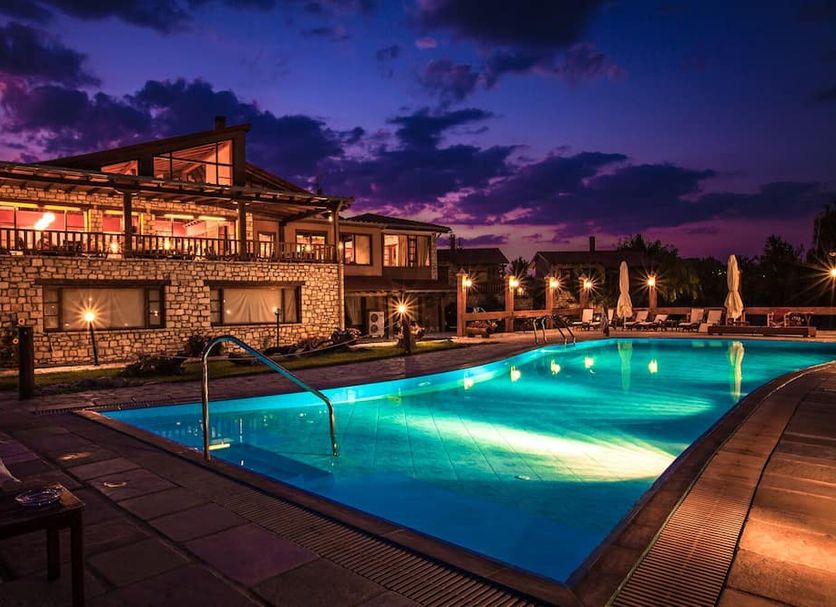 Vitina House in Vytina with lit outdoor pool and stone hotel exterior at dusk