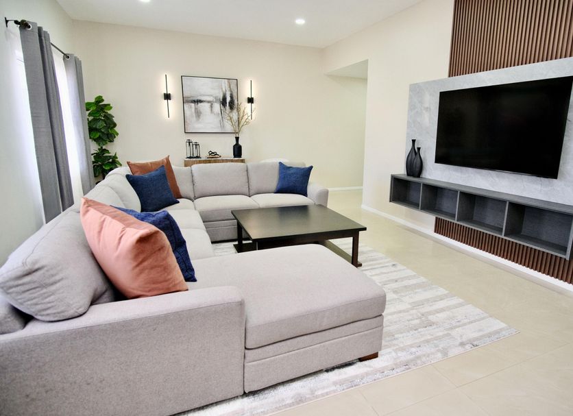 Rio Suites Tijuana living room with sectional sofa, coffee table, and wall-mounted TV
