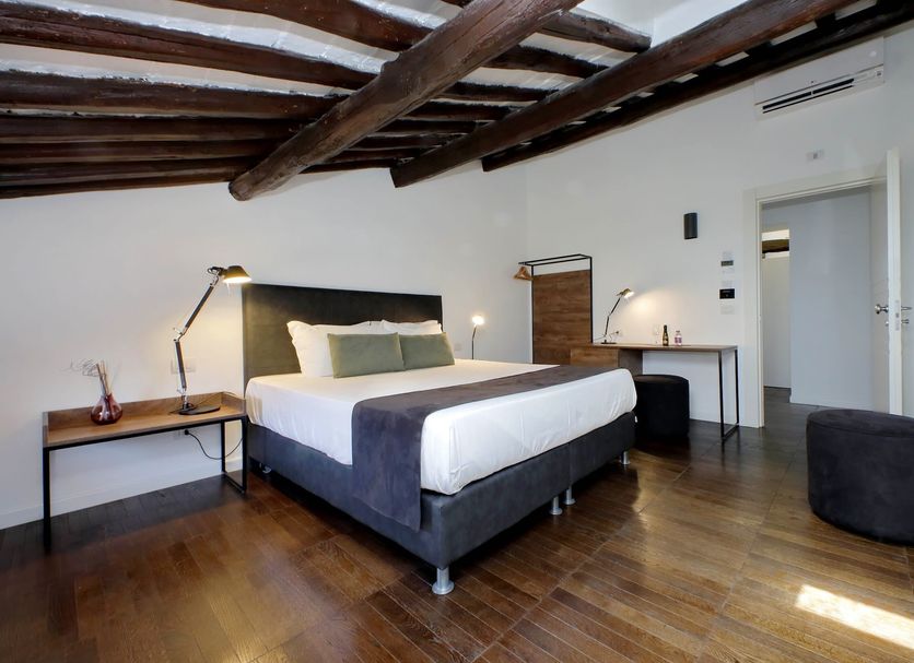 Youroom Corsini, Rome: modern bedroom with exposed wood beams, double bed, desk and wall-mounted TV