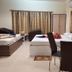 Hotel Sea Coast in Digha: family room with multiple beds, dining table and chairs, and curtained windows