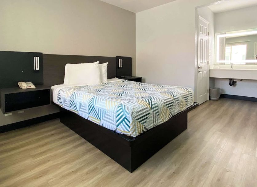 Motel 6 Costa Mesa guest room with bed, desk area, and large wall mirror